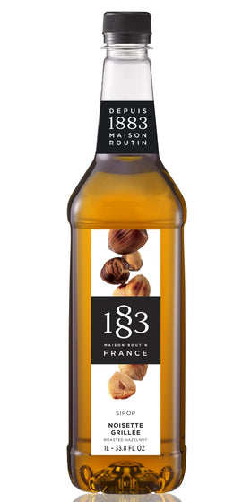 1883 Maison Routin roasted hazelnut syrup bottle on countertop for premium drinks.