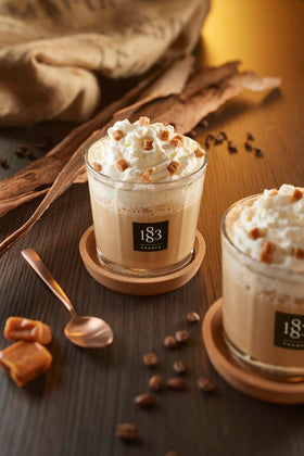 Coffee cup with 1883 sugar-free caramel syrup drizzle for lattes.