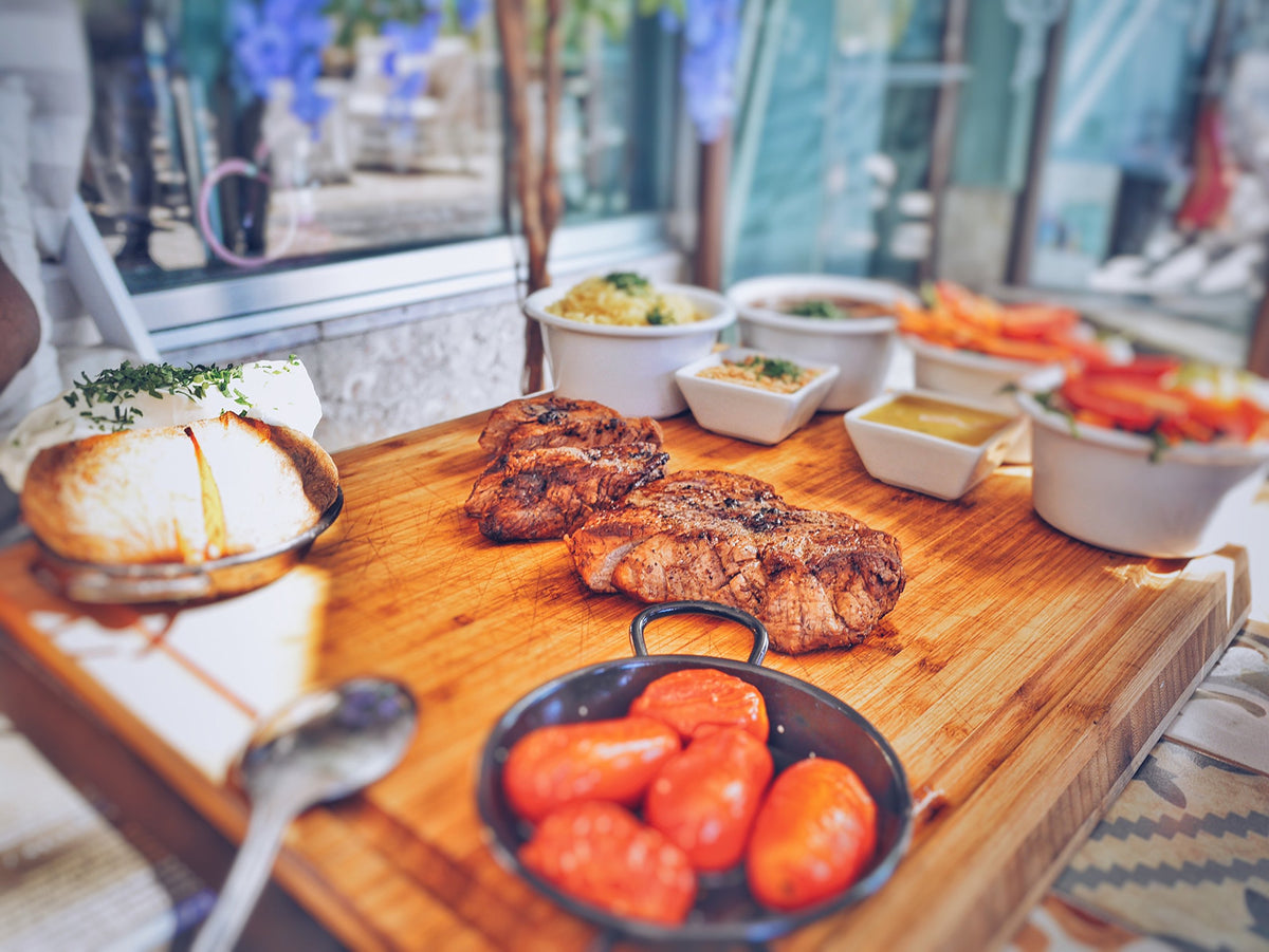 Adkins Ranch Style Steak Seasoning dispensing spice on prepared meat.