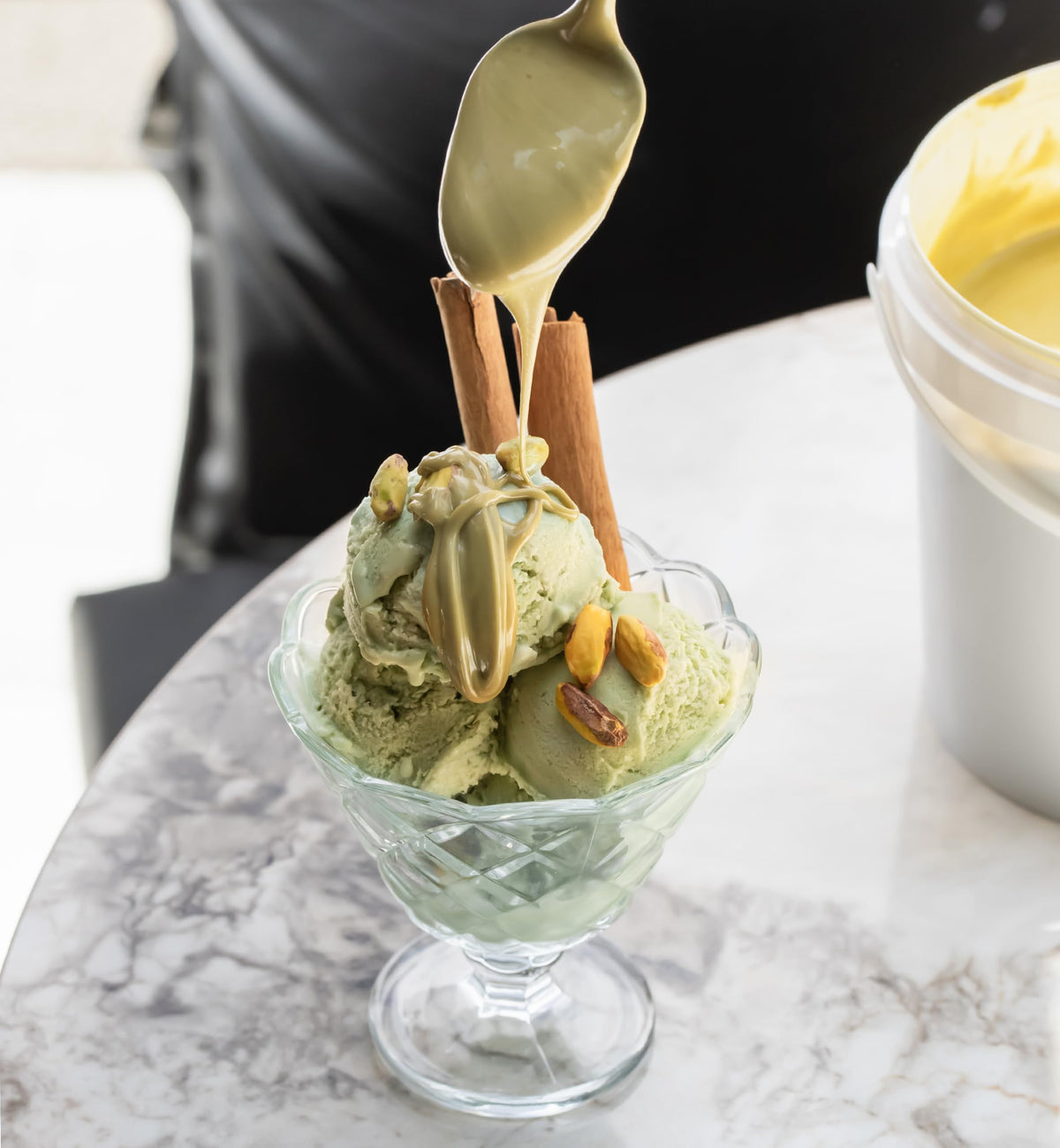 Cream swirls atop ice cream with Alkis Pistachio Cream.