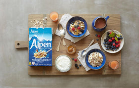 Alpen Muesli No Sugar Added ingredients arranged: wheat flakes, oats, nuts, raisins.