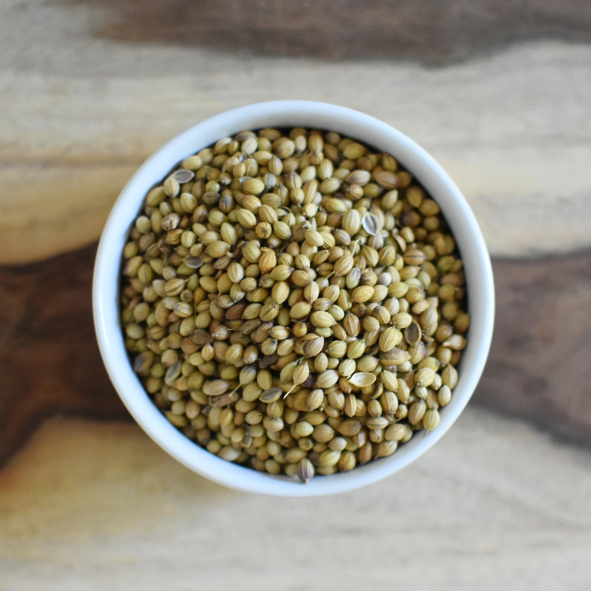 Anthony's Organic coriander seeds bottle on the counter with a spice grinder nearby.