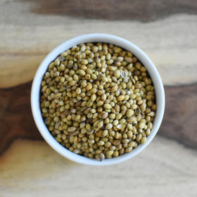 Anthony's Organic coriander seeds bottle on the counter with a spice grinder nearby.