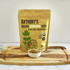 Anthony's Organic coriander seeds beside a mortar and pestle on the counter.