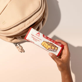 Hand holding Atkins Bar after bite, showcasing convenient on-the-go snacking.