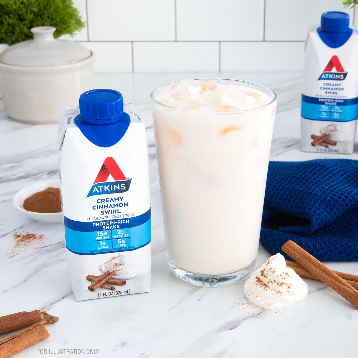 On-the-go Atkins Creamy Cinnamon Swirl bottle beside laptop to illustrate busy mornings.