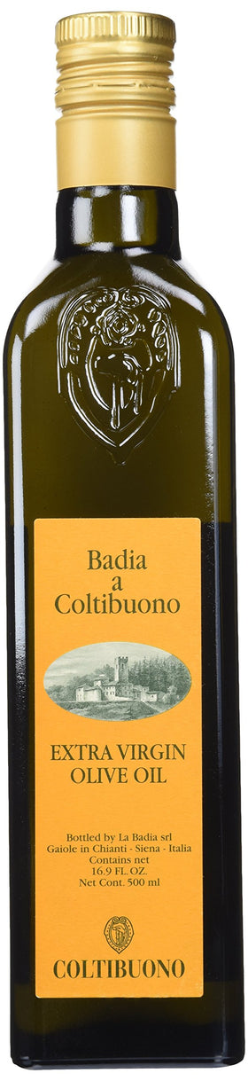 Badia a Coltibuono EVOO bottle on a rustic counter, ideal for finishing dishes.