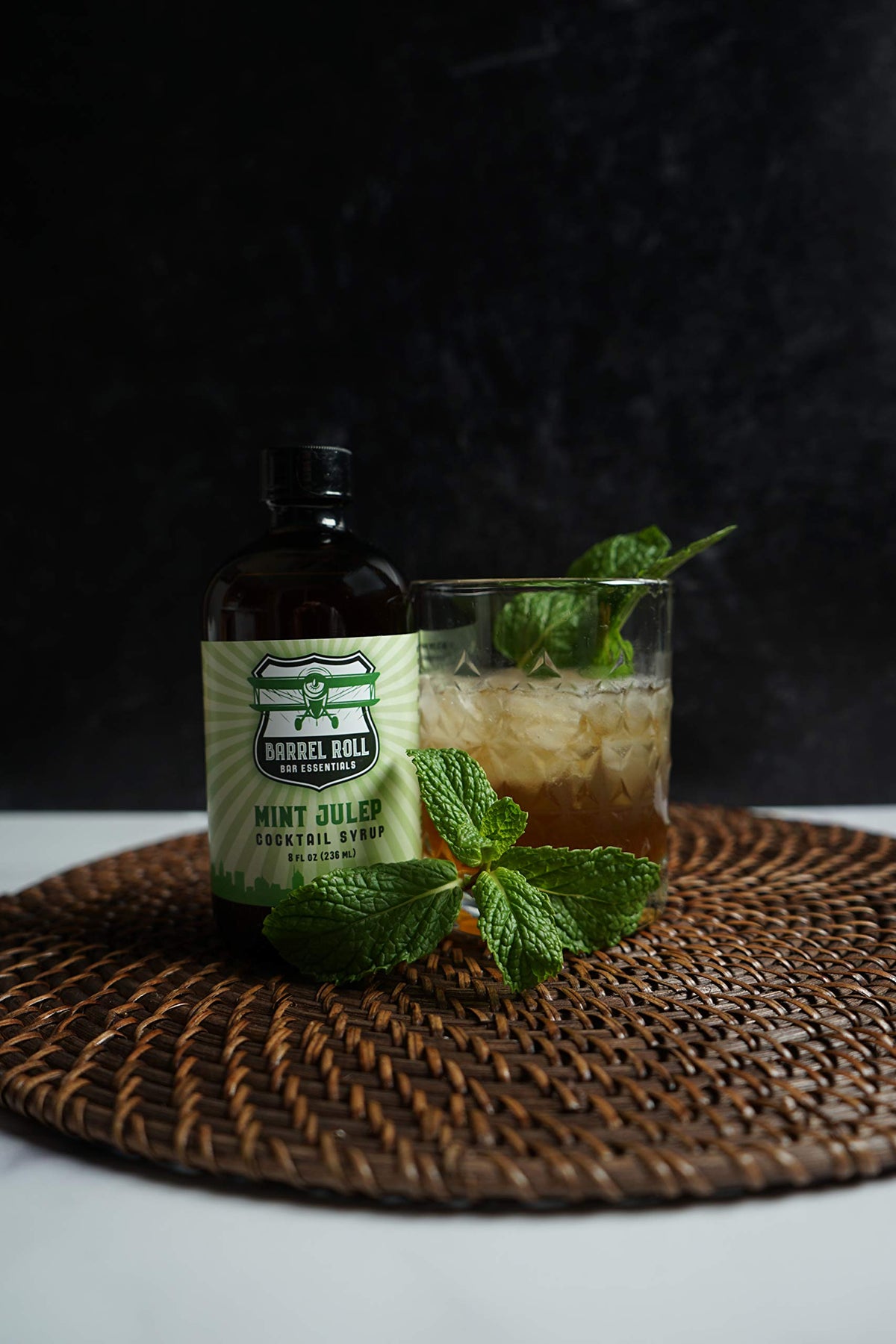 Pouring mint julep mix into glass with ice captures simple home bartending ritual.