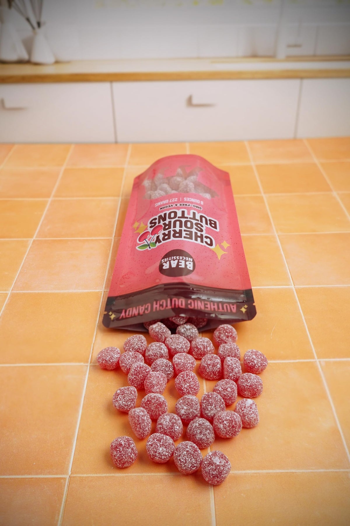 Bear Necessities Sour Buttons cherry close-up highlights glossy coating and vibrant cherry flavor.