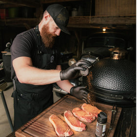 Brisket being seasoned with Black Blend during slow smoking