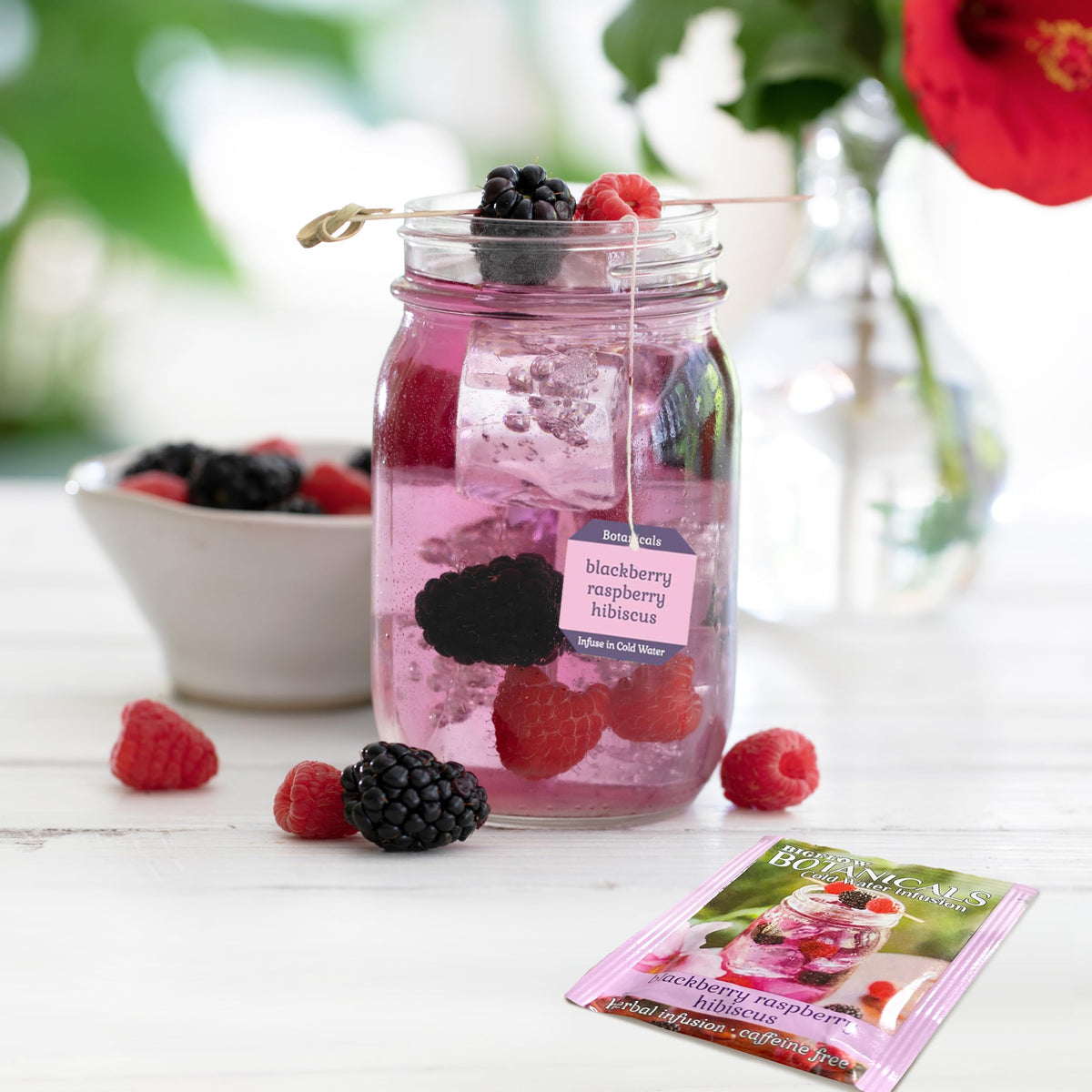 Tea bag in a glass of cold water highlighting caffeine-free, refreshing berry flavor.