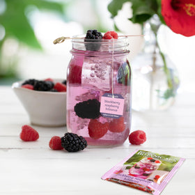 Tea bag in a glass of cold water highlighting caffeine-free, refreshing berry flavor.
