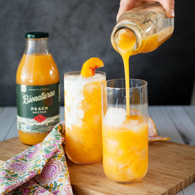 Bionaturae Organic Peach Nectar pour into glass, ideal for a sunny afternoon.