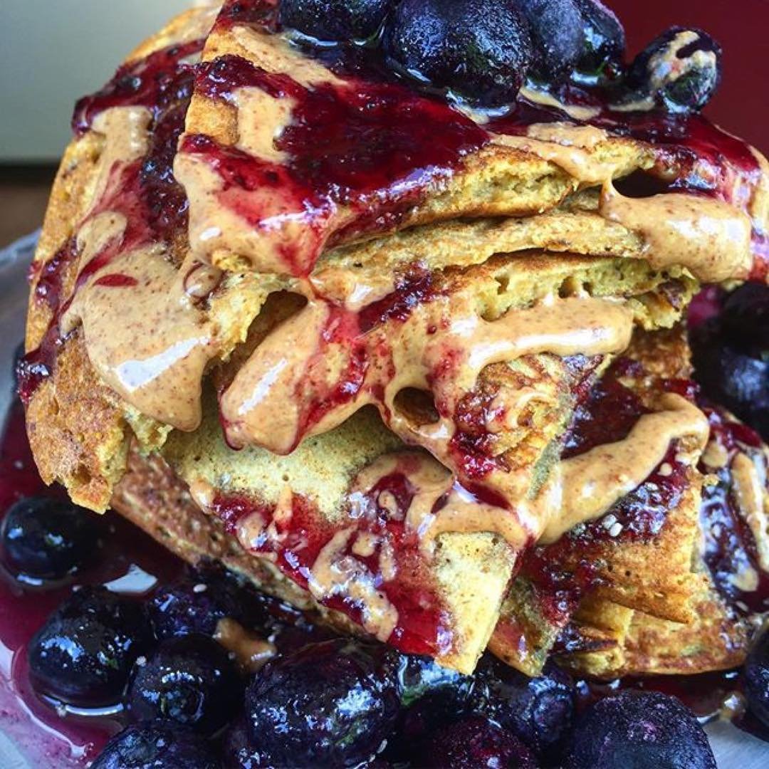 Syrup being poured over pancakes to reveal blueberry sweetness
