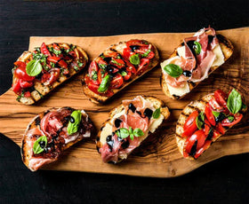 Blazing Bella bottle beside cheese board, pairs well with meats, cheeses, and bread