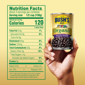 Pouring Bush's Best Organic Black Beans from a can into a pot for cooking.