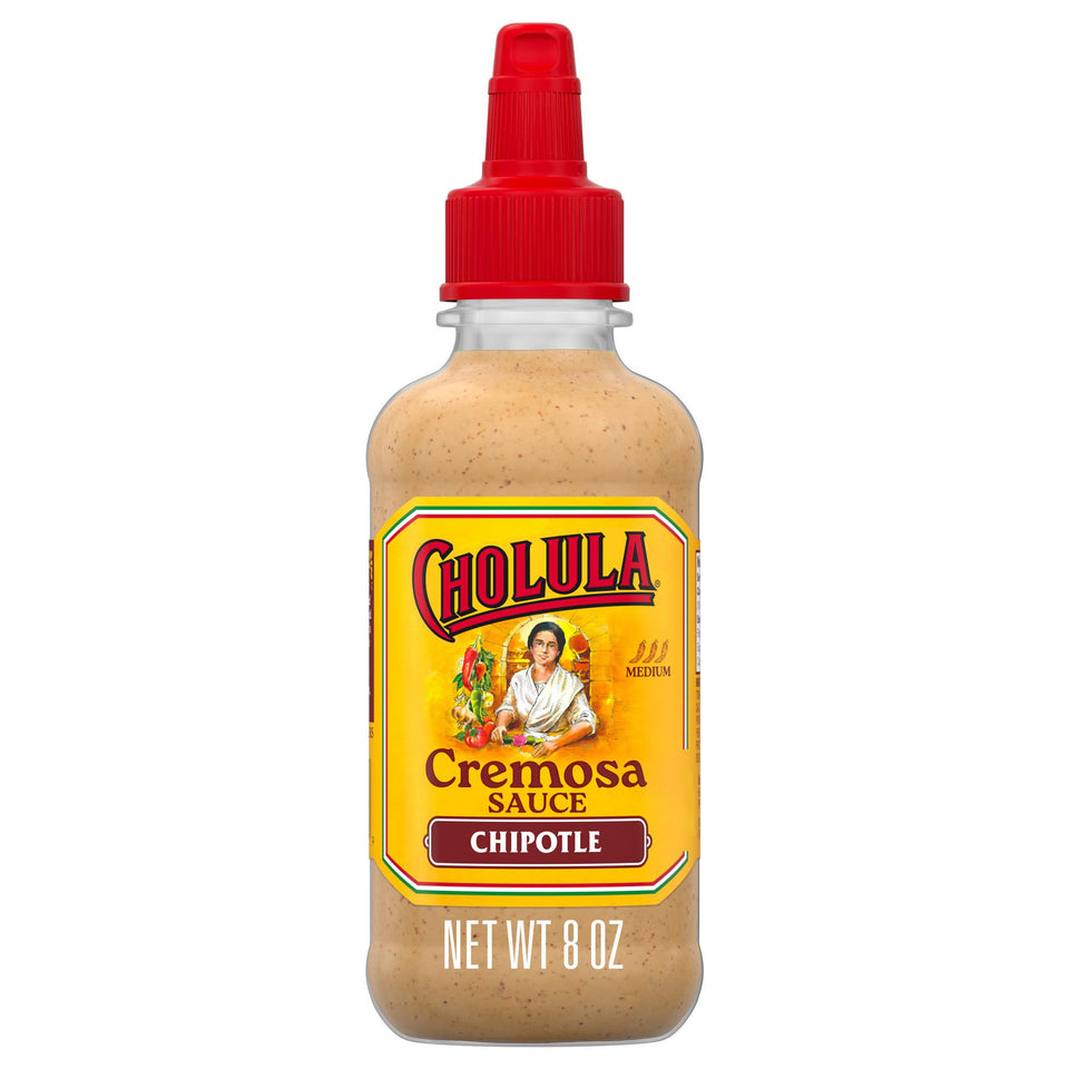 Cholula Chipotle Cremosa bottle drizzling onto tacos for smoky creaminess.