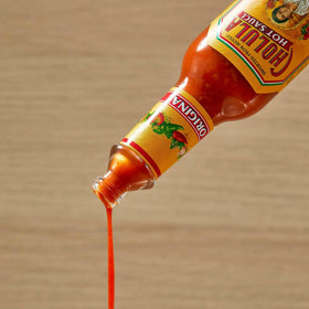 Cholula Original Hot Sauce bottle beside pizza flavor enhancer for dinners