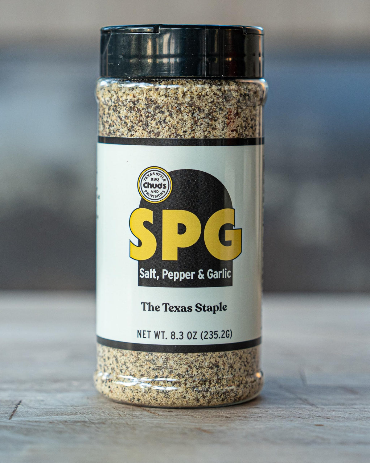 Chuds SPG salt pepper garlic rub bottle pouring for even seasoning on grilled foods.