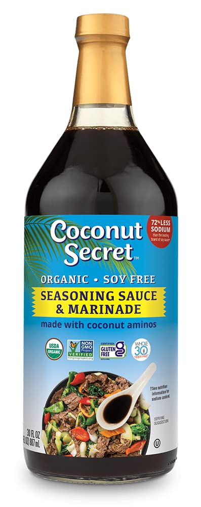 Coconut Secret Coconut Aminos bottle poured over a fresh salad to boost flavor