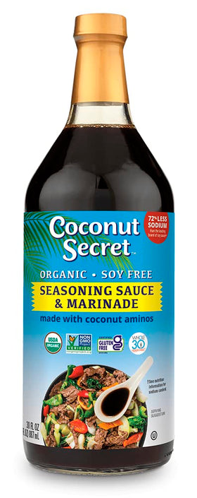 Coconut Secret Coconut Aminos bottle poured over a fresh salad to boost flavor