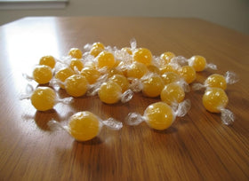 DM Sweets jumbo lemon candy balls on display dish, bright golden-yellow.