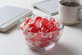 DM Sweets striped cinnamon discs in a clear bowl for office treat bowls.