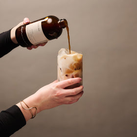 DONA Original Masala Chai Concentrate bottle beside glass ready for latte possibilities