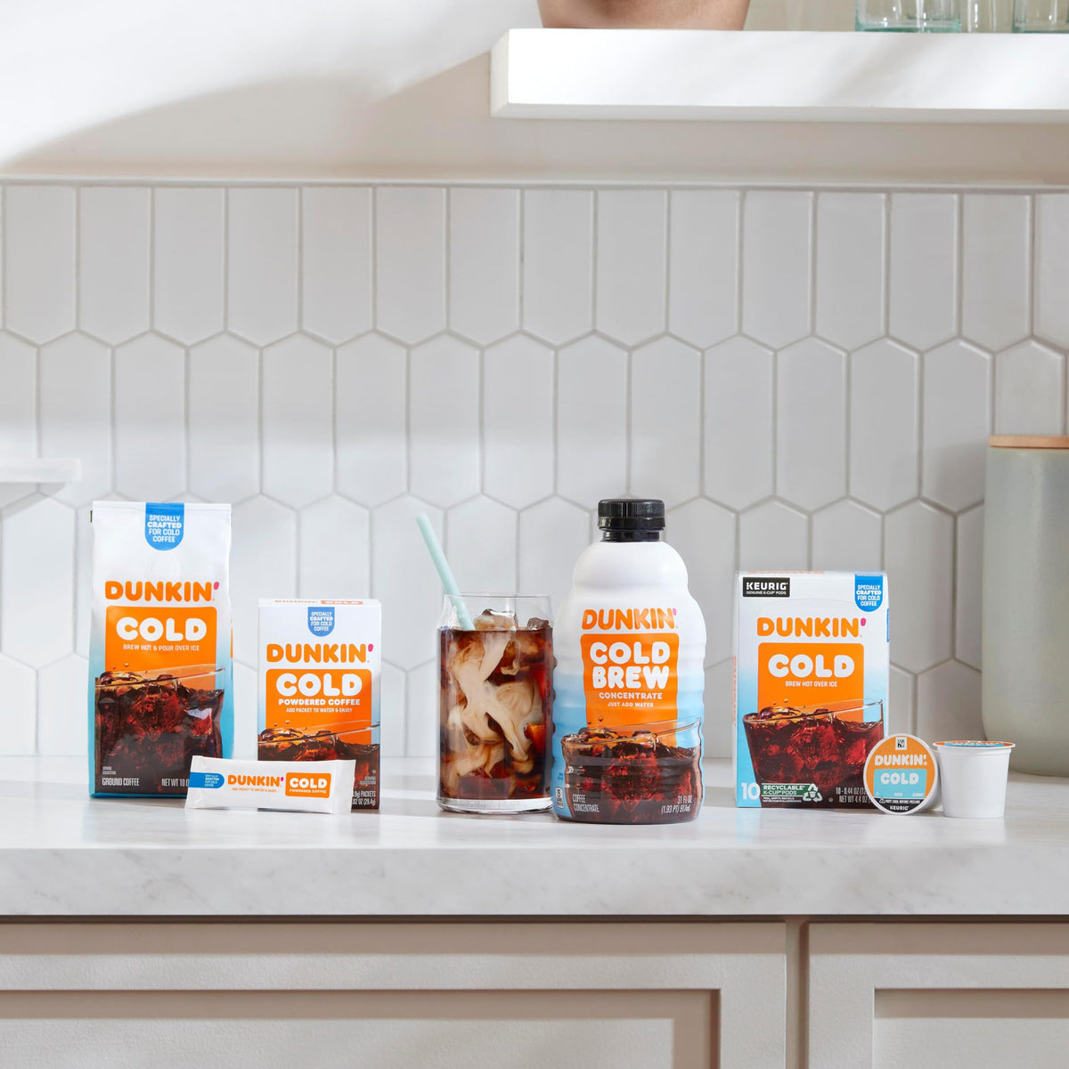 Dunkin Cold powder packets arranged beside a tall iced coffee.
