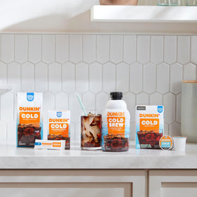 Dunkin Cold powder packets arranged beside a tall iced coffee.
