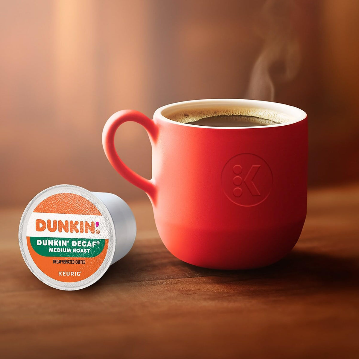 Single-serve Dunkin Decaf pod beside a steaming cup.