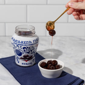 Fabbri Amarena cherries in syrup beside a glass bottle, ready to sweeten desserts.