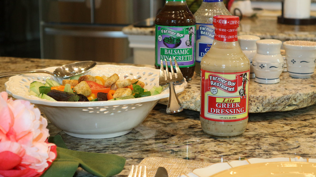 Farmer Boy Greek Lite Dressing being poured over greens for a zesty finish