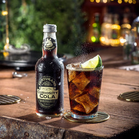 Chilled Fentimans Sparkling Curiosity Cola in a glass with citrus, ideal for cocktails.