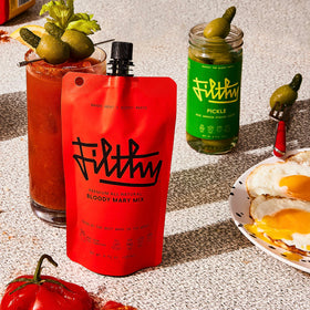 Filthy Food Bloody Mary Mix being poured into a glass for bar-quality flavor.