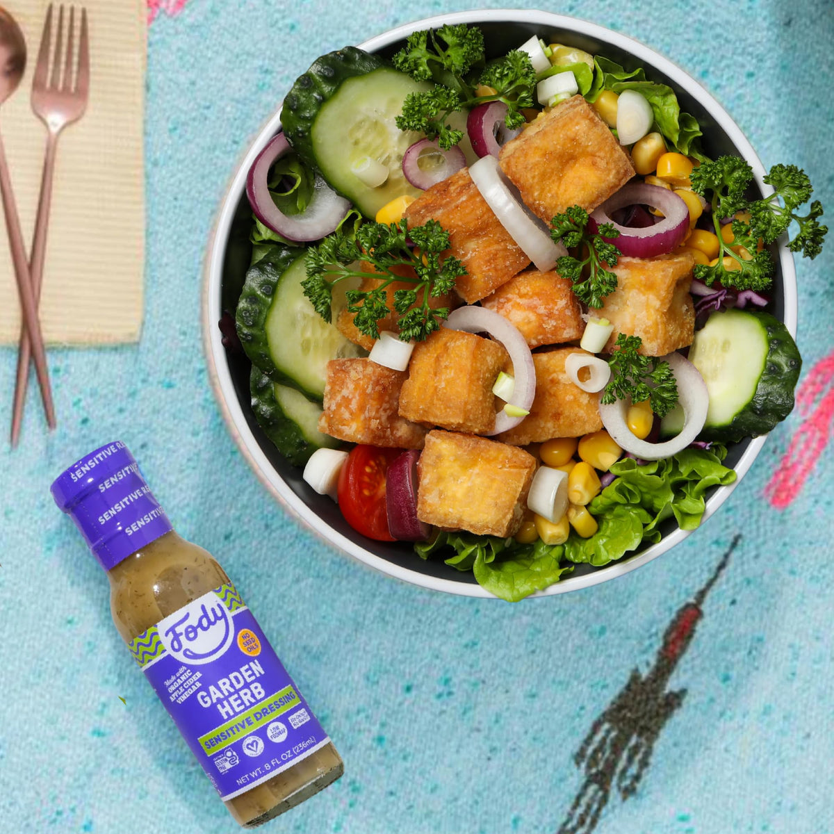 Glass of dressing beside a fresh salad featuring Fody Garden Herb, low FODMAP.
