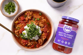 Close-up of tomato and basil ingredients beside Fody jar.