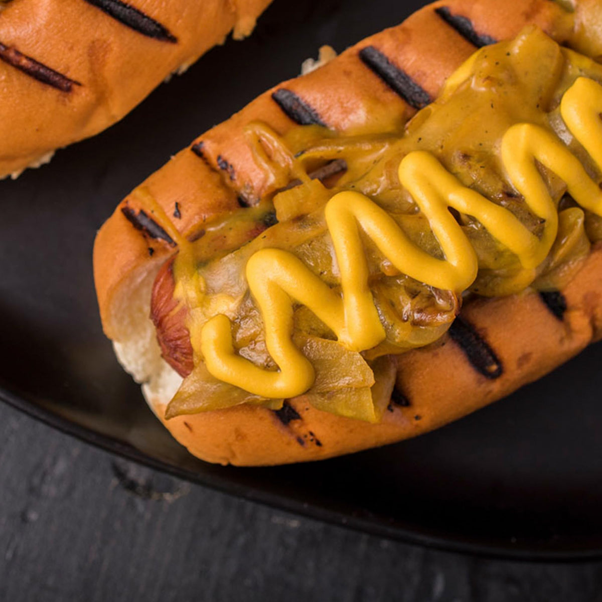 Squeeze bottle dispensing smooth yellow mustard onto a sandwich