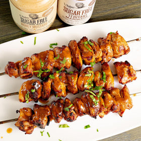 G Hughes Teriyaki Marinade glazing chicken skewers on the grill.