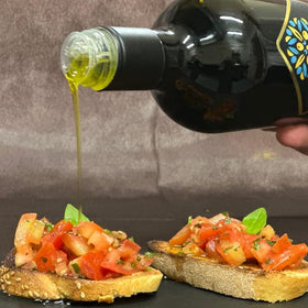 Galbasa olive oil being poured over bread for dipping.