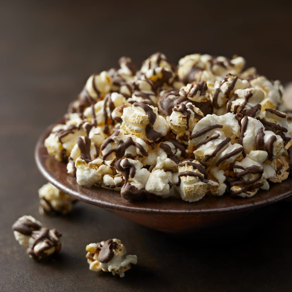 G.H. Cretors Dark Chocolatey Drizzle Popcorn closeup bite, rich chocolate drizzle on fluffy kernels.