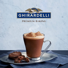 Pouring Ghirardelli cocoa into warm milk for a silky drink.