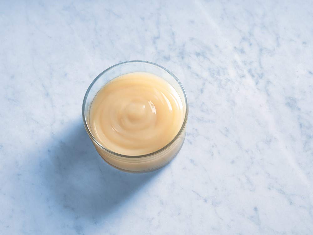 Ghirardelli white chocolate sauce being poured as a dessert topping