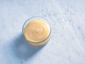Ghirardelli white chocolate sauce being poured as a dessert topping