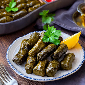 Serving bowl of Golden Harvest dolmas highlighting olive oil sheen.