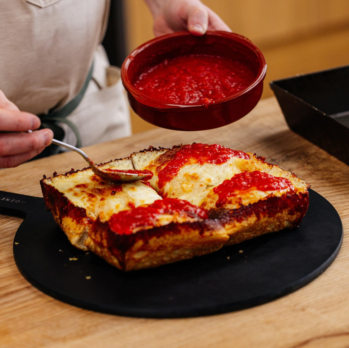 Gozney Detroit dough in oven, highlighting high-heat cooking for crisp edges.