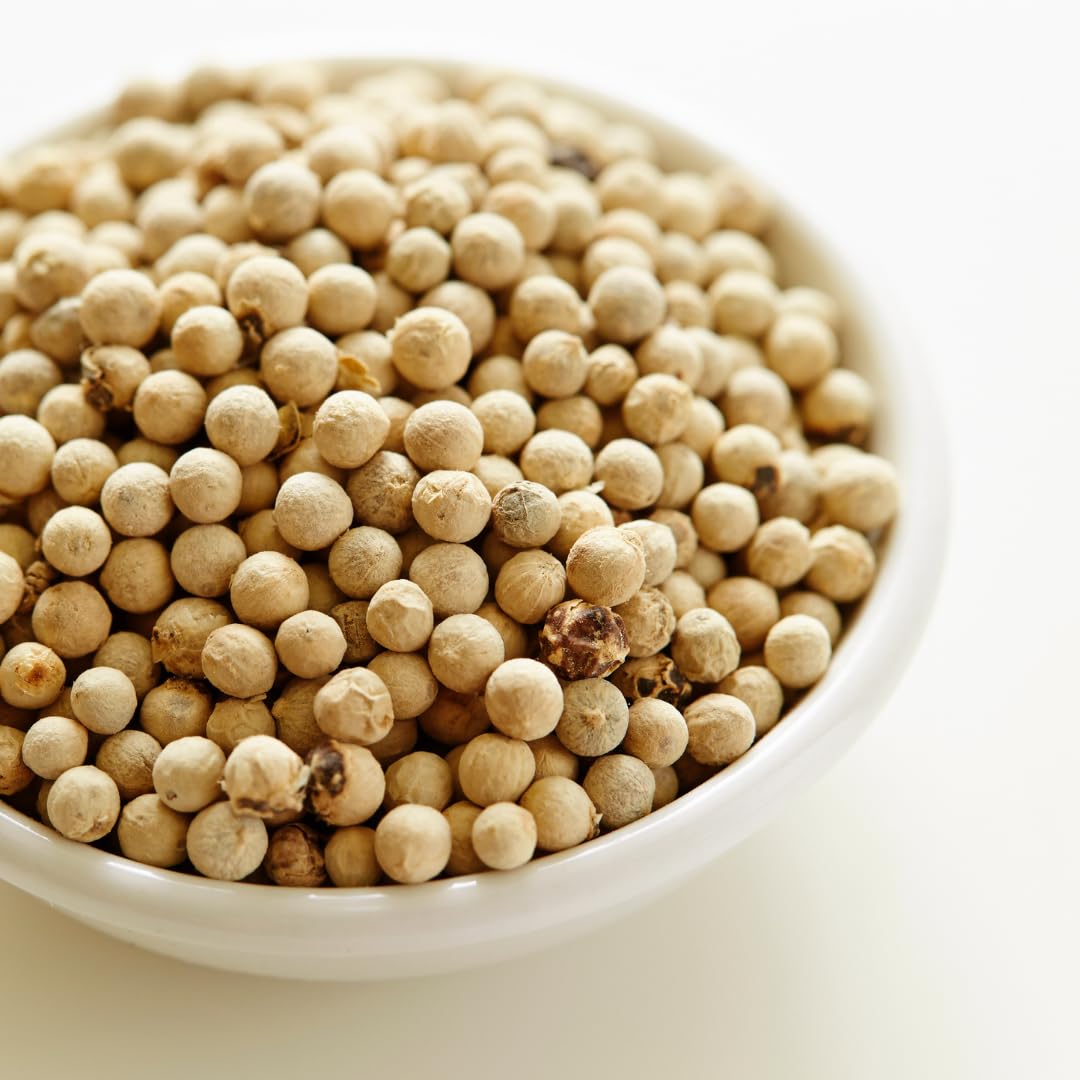 GranAroma white peppercorns displayed over a sauce bowl to brighten flavor.