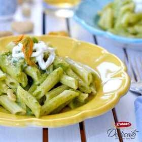 Granoro Dedicato Penne Rigate in a rustic kitchen with olive oil drizzle.