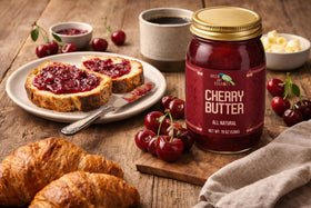 Green Jay Gourmet Cherry Butter jar with fresh cherries, versatile for desserts and savory dishes.