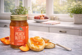Green Jay Gourmet Peach Butter jar pouring onto a spoon for tasting